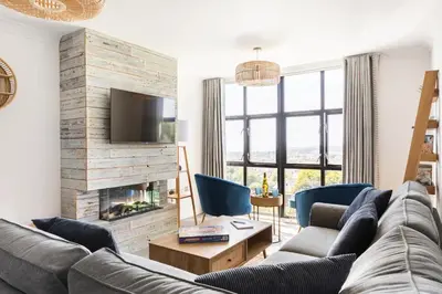 a living room with a couch and a fireplace at 5 mins from the Eden Project Baybreeze Holiday Apartment, Sea Views, Super Kingsize Beds in St Austell