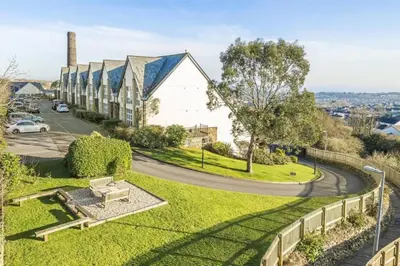 a park with a bench and a building at 5 mins from the Eden Project Baybreeze Holiday Apartment, Sea Views, Super Kingsize Beds in St Austell