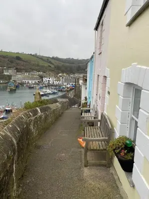 a couple of benches sitting next to a building at 5 mins from the Eden Project Baybreeze Holiday Apartment, Sea Views, Super Kingsize Beds in St Austell
