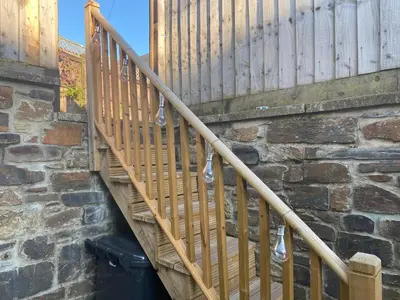 a wooden staircase next to a brick wall at Bodmin Rest 4 U in Bodmin