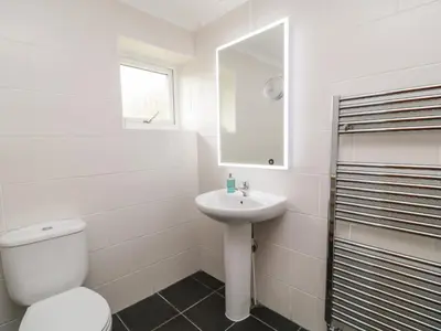 a white bathroom with a toilet and a sink at Looe Island View in Torpoint