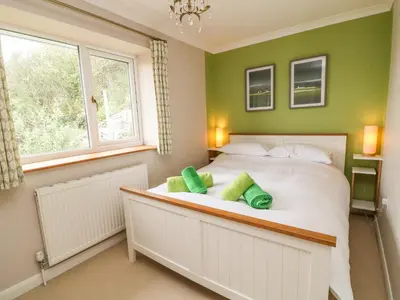 a bedroom with a large white bed with green walls at Looe Island View in Torpoint