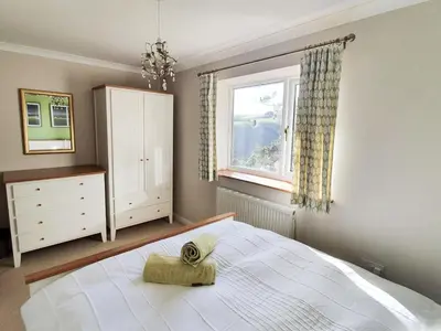 a bedroom with a large bed and a window at Looe Island View in Torpoint