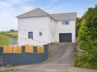 a white house with a garage on a driveway at Looe Island View in Torpoint