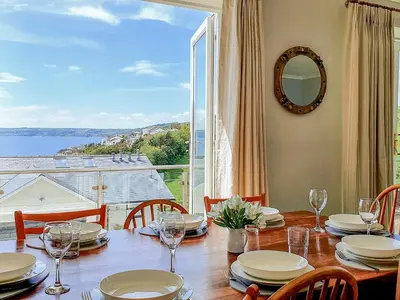 a dining room with a table and a large window at Looe Island View in Torpoint