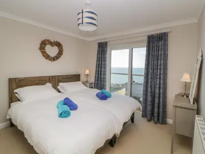 a bedroom with two beds and a large window at Looe Island View in Torpoint