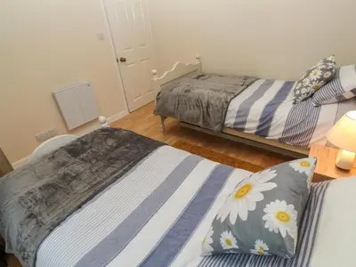 a bedroom with two beds and a bed with flowers at 11 Tremore in Liskeard