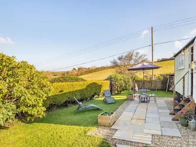 a garden with a patio and an umbrella at Shepherds Retreat in St Austell