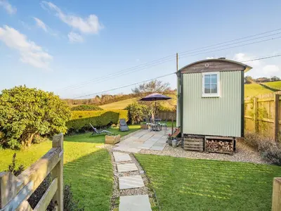 a small green building with an umbrella in a yard at Shepherds Retreat in St Austell