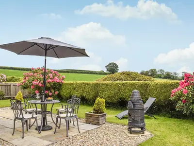 a patio with a table and an umbrella at Shepherds Retreat in St Austell
