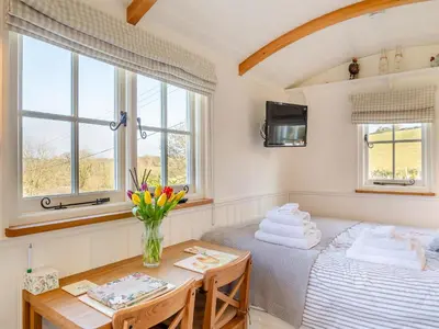 a room with a bed and a table and windows at Shepherds Retreat in St Austell