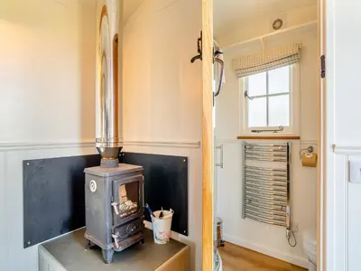 a wood stove in a room with a window at Shepherds Retreat in St Austell