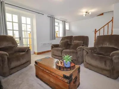 a living room with three chairs and a coffee table at Miners cottage in St Austell