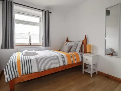 a white bedroom with a bed and a window at Miners cottage in St Austell