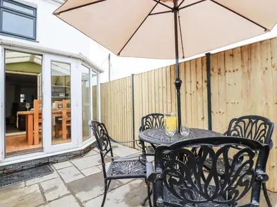 a table and chairs with an umbrella on a patio at Miners cottage in St Austell