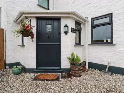 a black door on a white house with plants at Miners cottage in St Austell