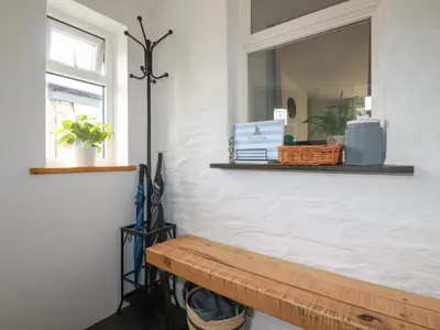 a bench in a room with a mirror and a window at Miners cottage in St Austell