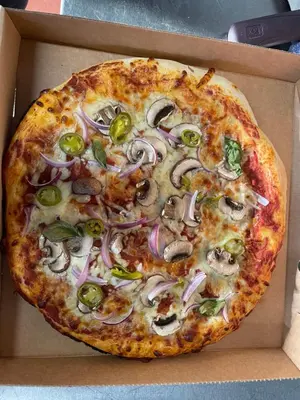 a pizza with onions and peppers in a box at Wayfarers Inn in Penzance