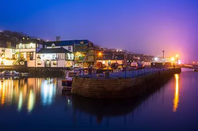 a boat is docked in a marina at night at The Nest, Central Falmouth, 10 mins to the beaches and off street parking in Falmouth