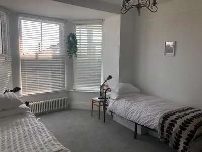 two beds in a room with two windows at The Nest, Central Falmouth, 10 mins to the beaches and off street parking in Falmouth