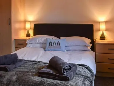 a bedroom with a large bed with towels on it at Picturesque Cabin in Cornwall in Camborne