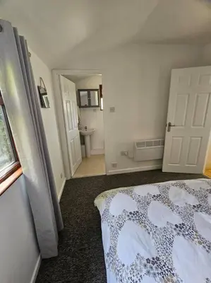 a bedroom with a bed and a bathroom at Picturesque Cabin in Cornwall in Camborne