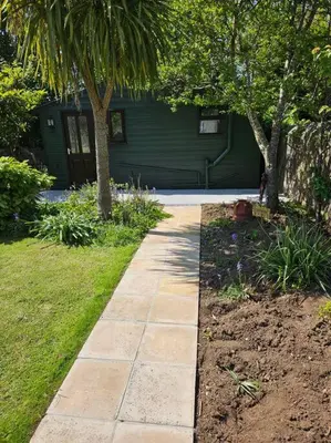 a stone walkway in front of a green house at Picturesque Cabin in Cornwall in Camborne