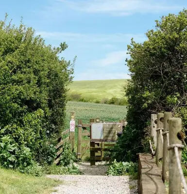 a wooden gate leading to a field with a fence at No14 Padstow in Padstow