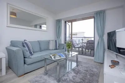 a living room with a couch and a table at Fistral View, Pentire - Parking, Sea view, free Wifi in Newquay