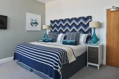 a bedroom with a large bed with blue and white stripes at Harbour Hotel Padstow in Padstow