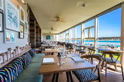 a restaurant with tables and chairs with a view of the ocean at Harbour Hotel Padstow in Padstow