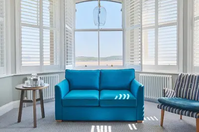 a blue couch in a room with windows at Harbour Hotel Padstow in Padstow