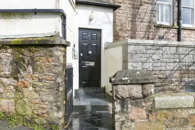 a black door on a house with a stone wall at Arghanti in St Ives