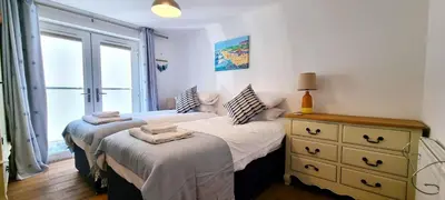 a bedroom with two beds and a dresser and a window at No 1 Oceans in Perranporth