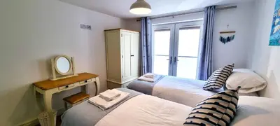 a small room with two beds and a mirror at No 1 Oceans in Perranporth