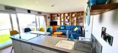 a kitchen and living room with a blue couch at No 1 Oceans in Perranporth