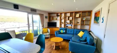 a living room with a blue couch and a table at No 1 Oceans in Perranporth