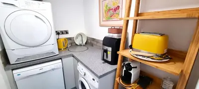 a small kitchen with a washing machine and a microwave at No 1 Oceans in Perranporth
