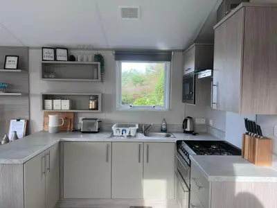 a kitchen with white cabinets and a window at Porthcurno 4, Silverbow Country Park in Perranzabuloe