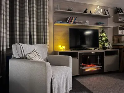 a living room with a television and a chair and a christmas tree at Porthcurno 4, Silverbow Country Park in Perranzabuloe