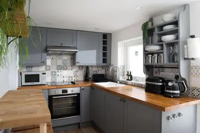 a kitchen with gray cabinets and a wooden counter top at Peaceful & Tranquil Cottage With Private Terrace at 'The Pink House' in Falmouth