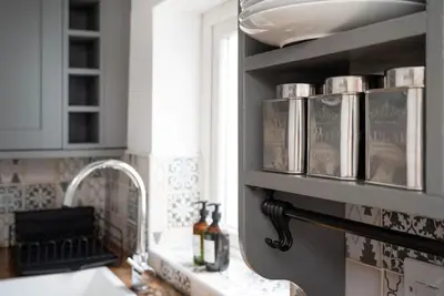 a kitchen with a sink and a shelf with books at Peaceful & Tranquil Cottage With Private Terrace at 'The Pink House' in Falmouth
