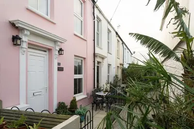 an alley with tables and chairs in a pink building at Peaceful & Tranquil Cottage With Private Terrace at 'The Pink House' in Falmouth