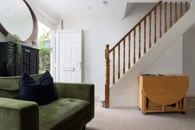 a living room with a green couch and a staircase at Peaceful & Tranquil Cottage With Private Terrace at 'The Pink House' in Falmouth