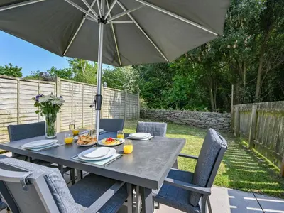 a table and chairs with an umbrella on a patio at Holiday Home Sea Breeze by Interhome in St Austell