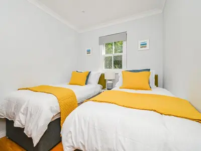 two beds in a white room with yellow pillows at Holiday Home Sea Breeze by Interhome in St Austell