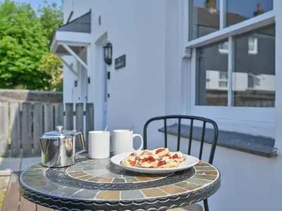 a plate of food on a table on a patio at Holiday Home Sea Breeze by Interhome in St Austell