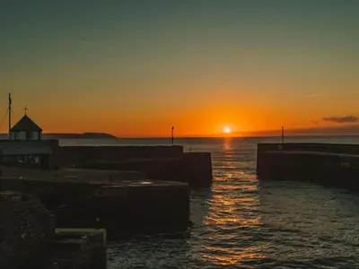 a sunset over a body of water with a dock at Holiday Home Sea Breeze by Interhome in St Austell