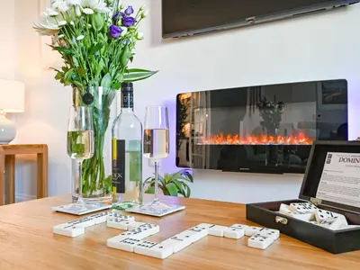 a table with a bottle of wine and a vase of flowers at Holiday Home Sea Breeze by Interhome in St Austell