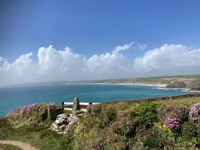 a bench on a hill next to a body of water at Olive's Cabin in Helston